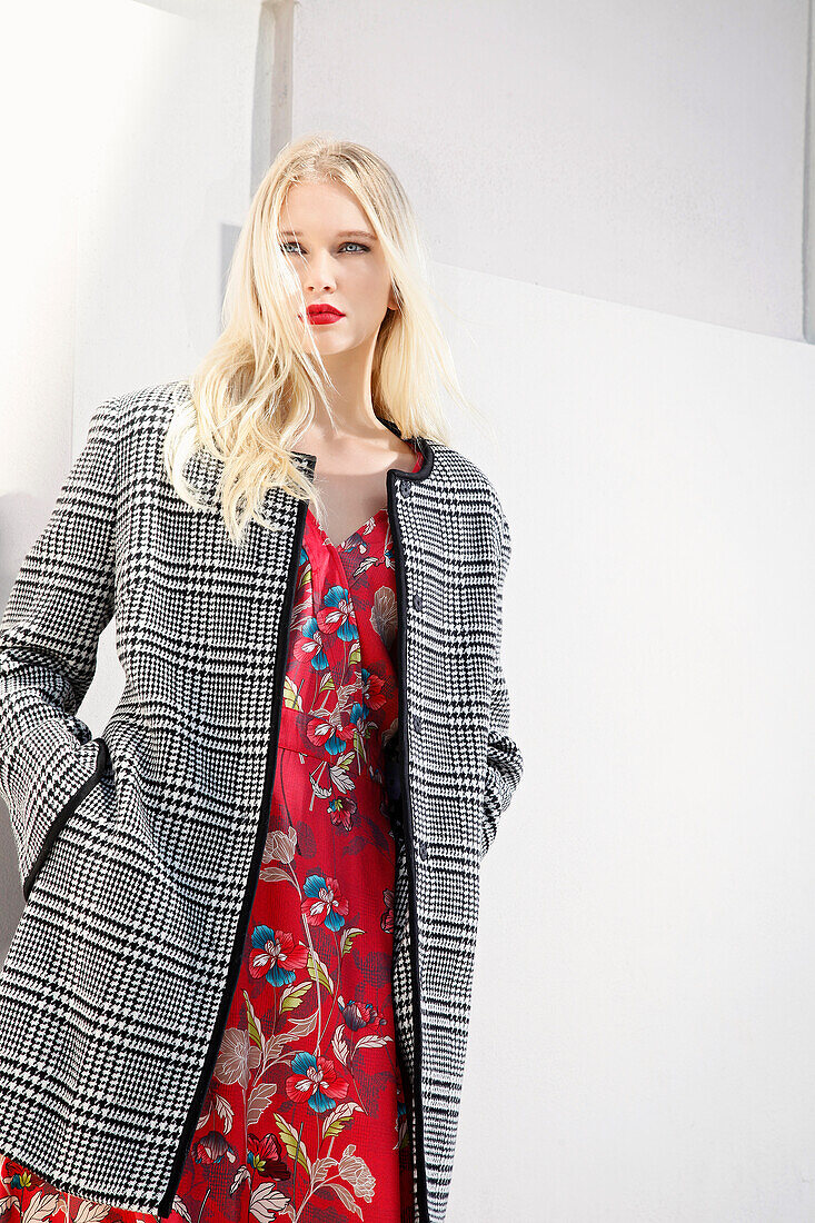 Young blond woman in red floral dress and checked coat