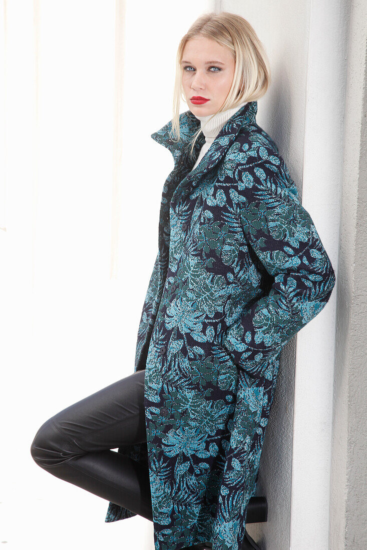 Young blond woman in transitional coat with leaf jacquard