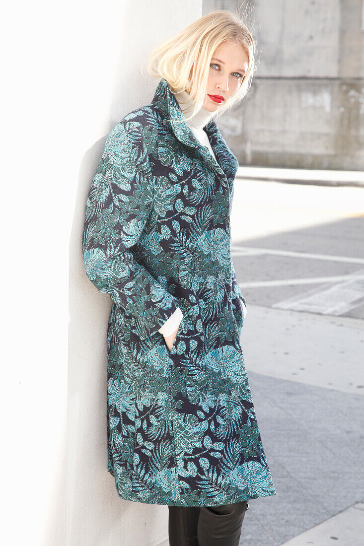 Young blond woman in transitional coat with leaf jacquard