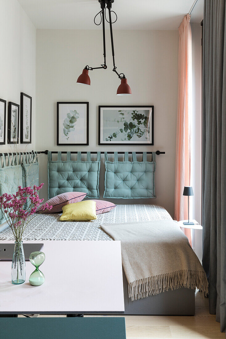 Bedroom with turquoise cushions and eucalyptus pictures on the wall