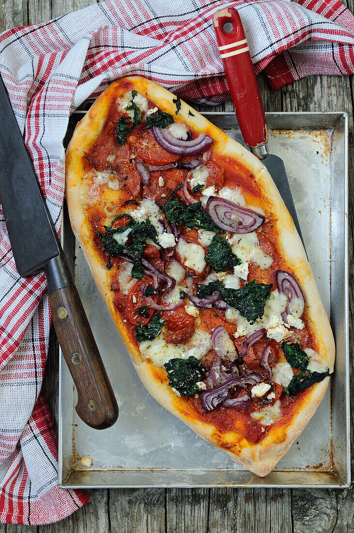 Homemade pizza with spinach, onions, pepperoni and mozzarella cheese