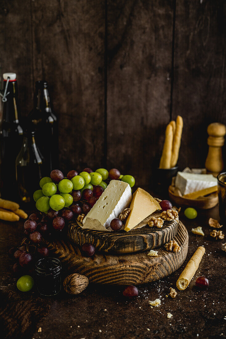 Cheese board with fruit on a dark wooden background