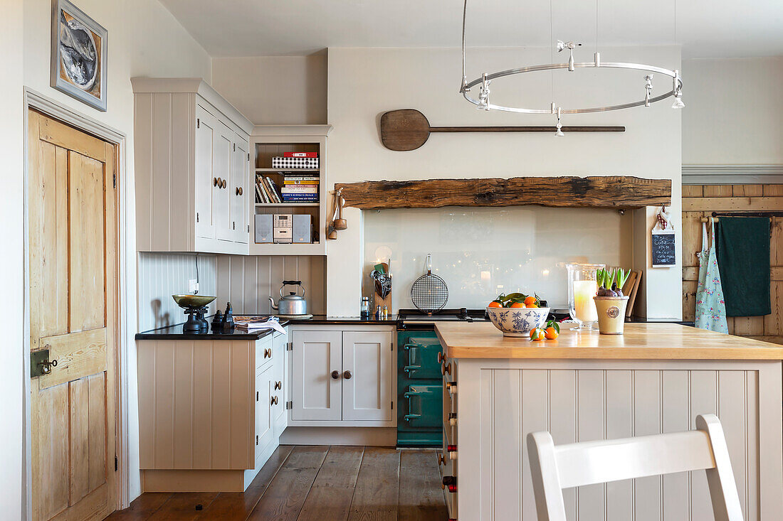 Country kitchen in white with exposed wooden beams and cooking island