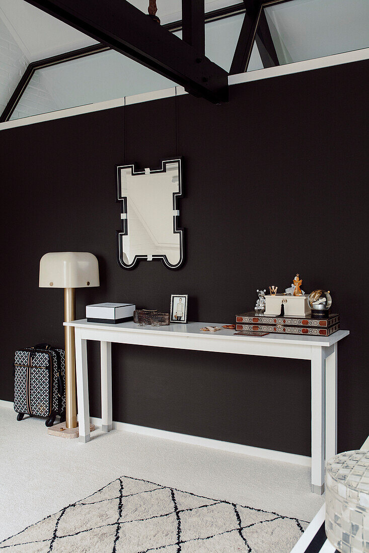 White console, mirror above on a black wall in a modern ambience