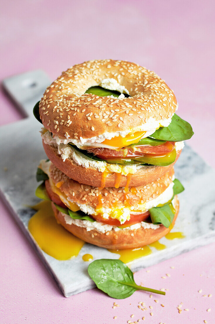 Bagel sandwiches with fried egg, lettuce, tomato and cream cheese