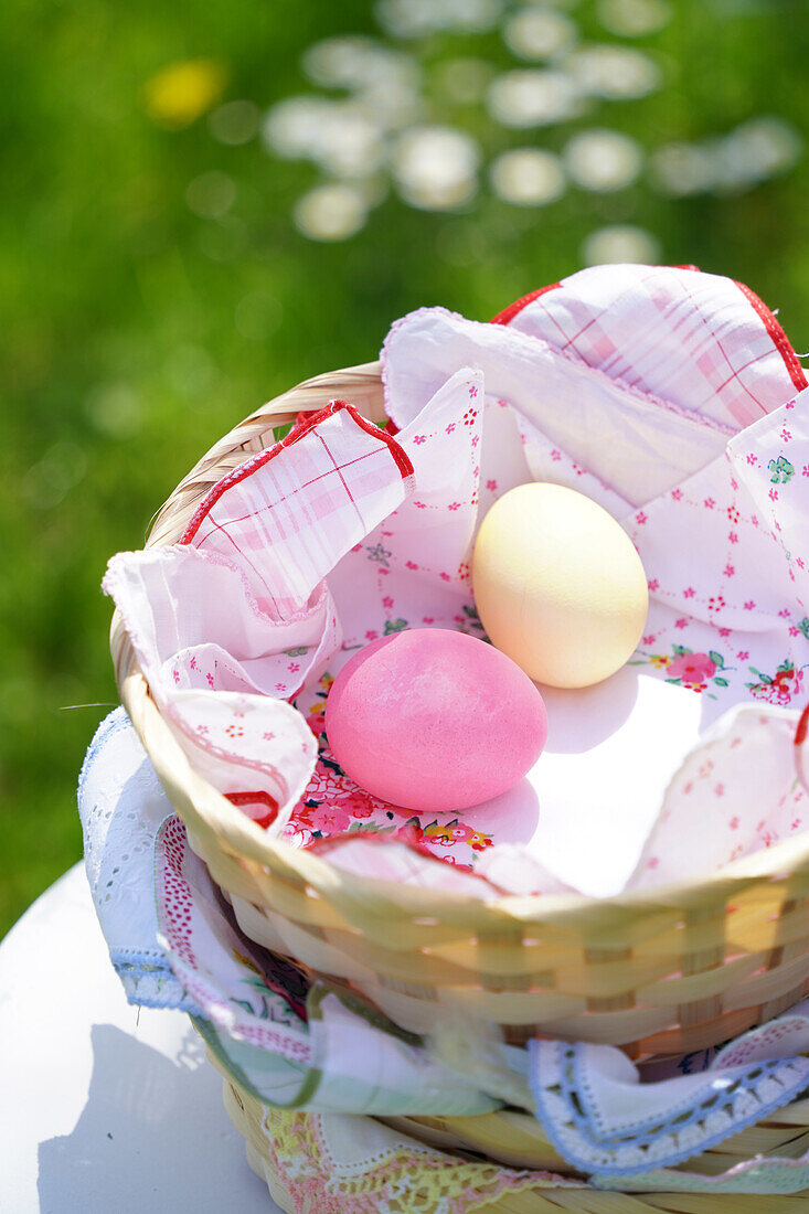 Osterkorb mit bunten Eiern auf einer Wiese im Frühling