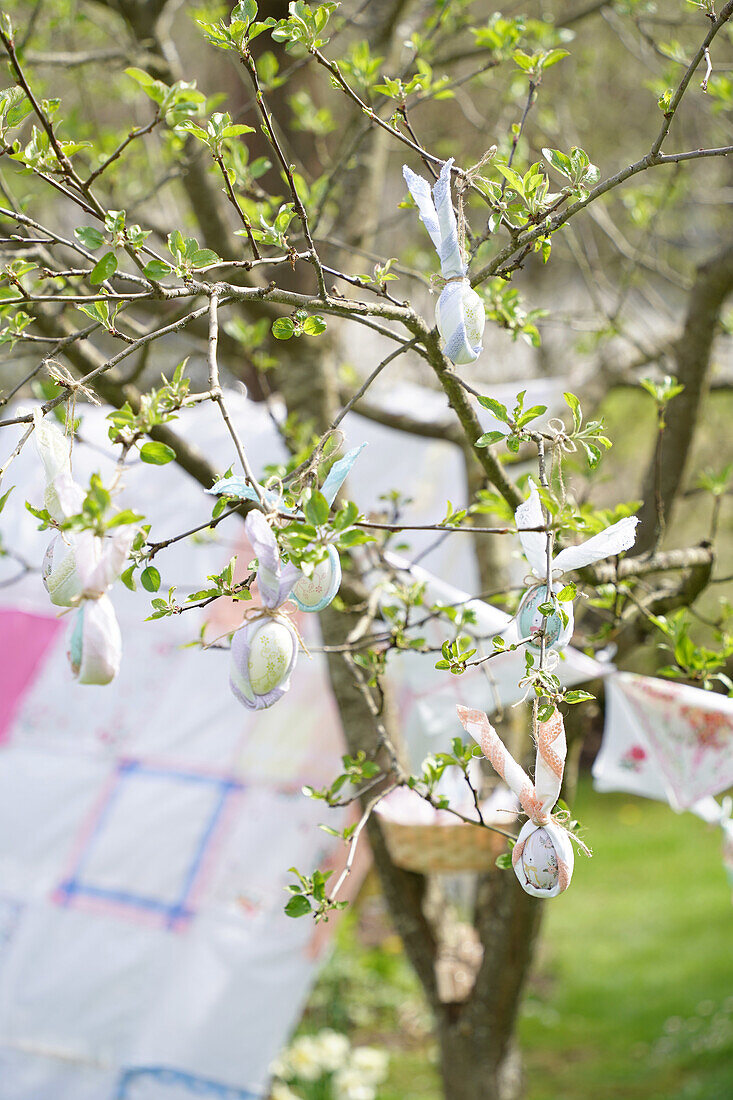 Apfelbaum mit österlicher Dekoration und Wimpelkette im Garten