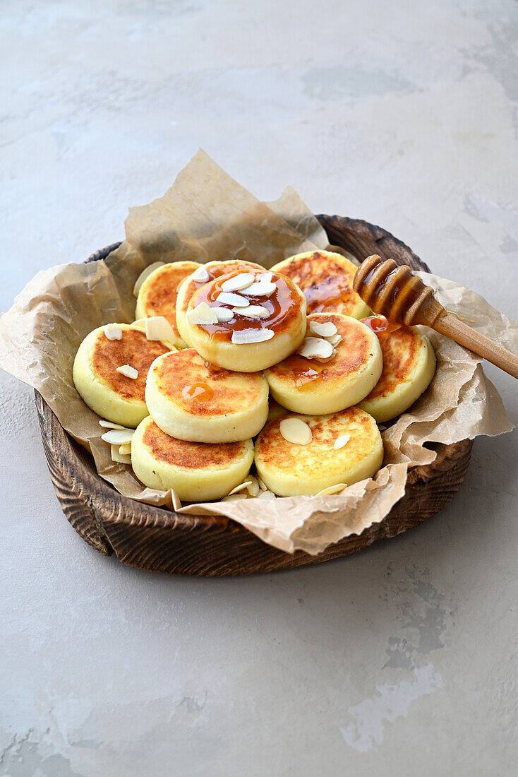 Syrniki (russische Frischkäse-Pfannkuchen) mit Honig und Mandeln