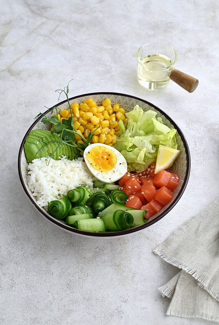 Bowl mit Lachs, Avocado, Mais, Eisbergsalat und Gurke