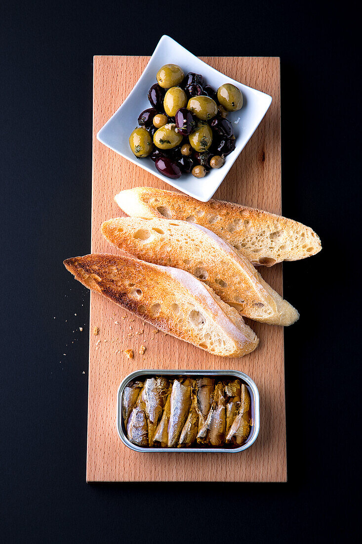 Ölsardinen, Röstbrot und eingelegte Oliven