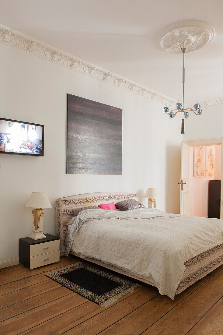 Doppelbett in Altbau-Schlafzimmer mit Stuckarbeit und Holzdielenboden