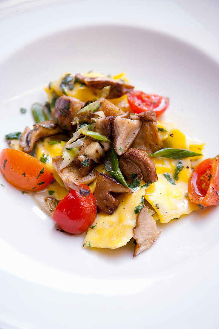 Ravioli with tomatoes, mushrooms and spring onions