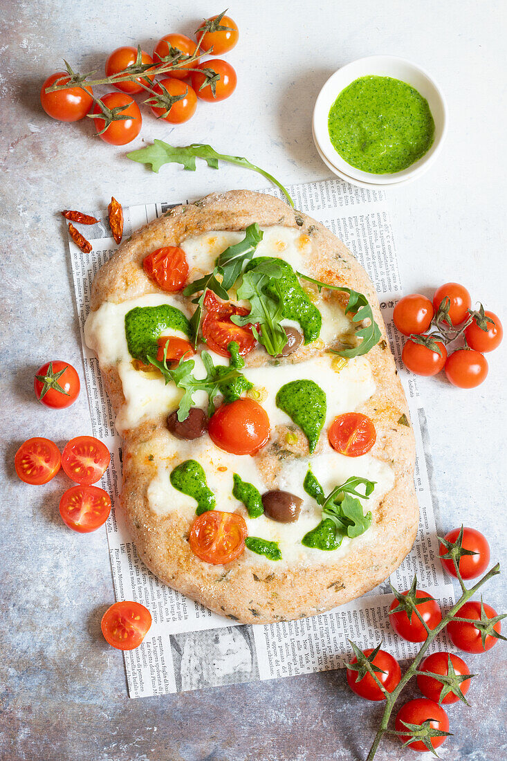 Pizza with aromatic herbs, mozzarella, tomatoes and pesto