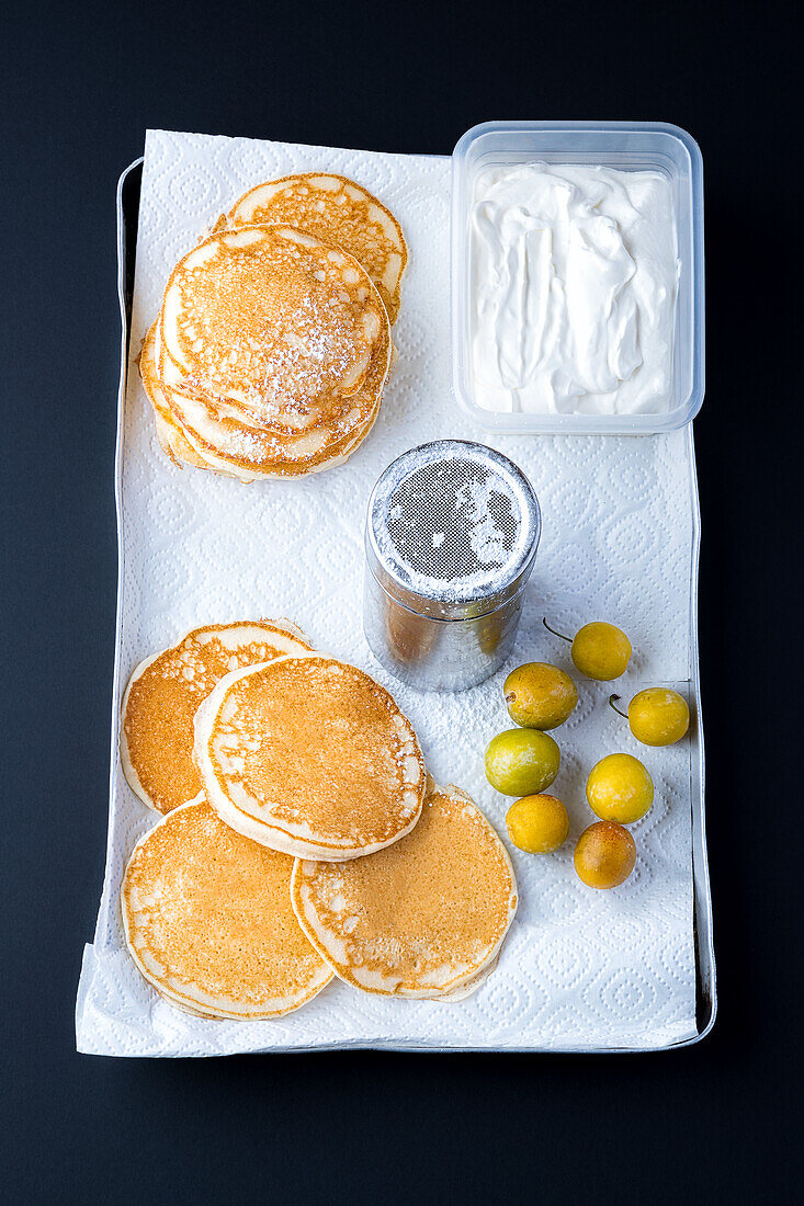 Pancakes, cream, mirabelles and powdered sugar