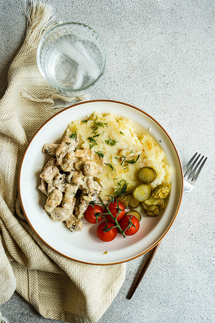 Pork sausage in sour cream sauce with mashed potatoes and vegetables