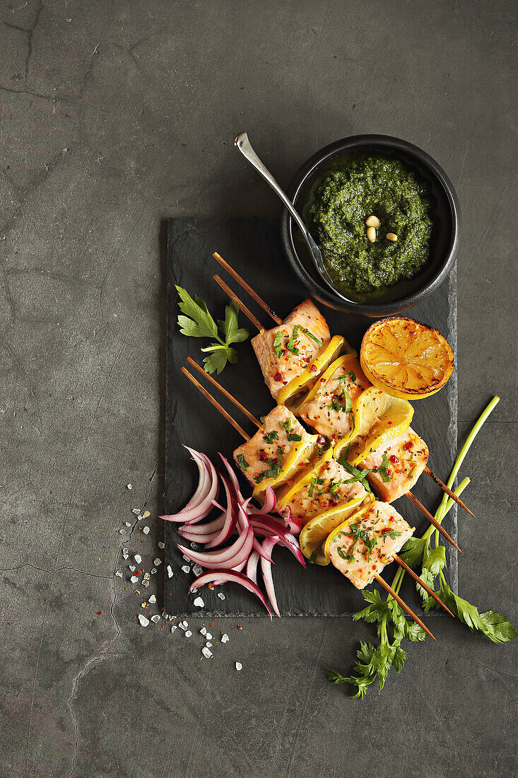 Spicy salmon skewers with citrus fruits and parsley pesto
