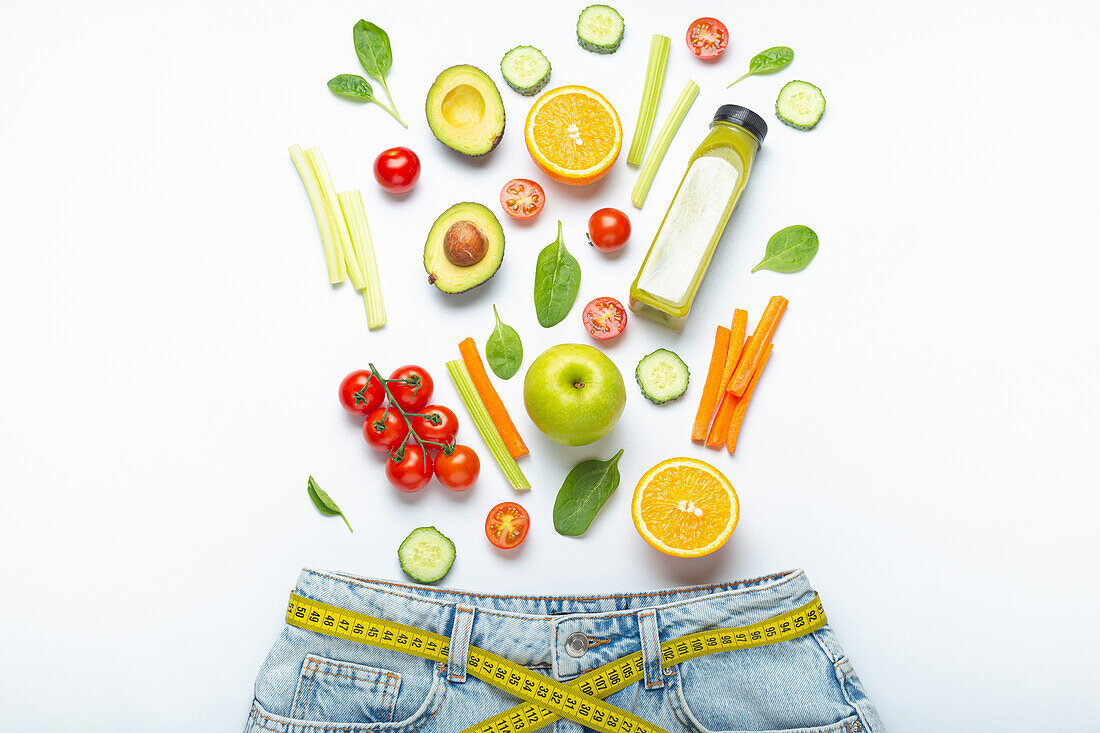 Fresh fruit, vegetables and smoothie fall in jeans with yellow tape measure as belt