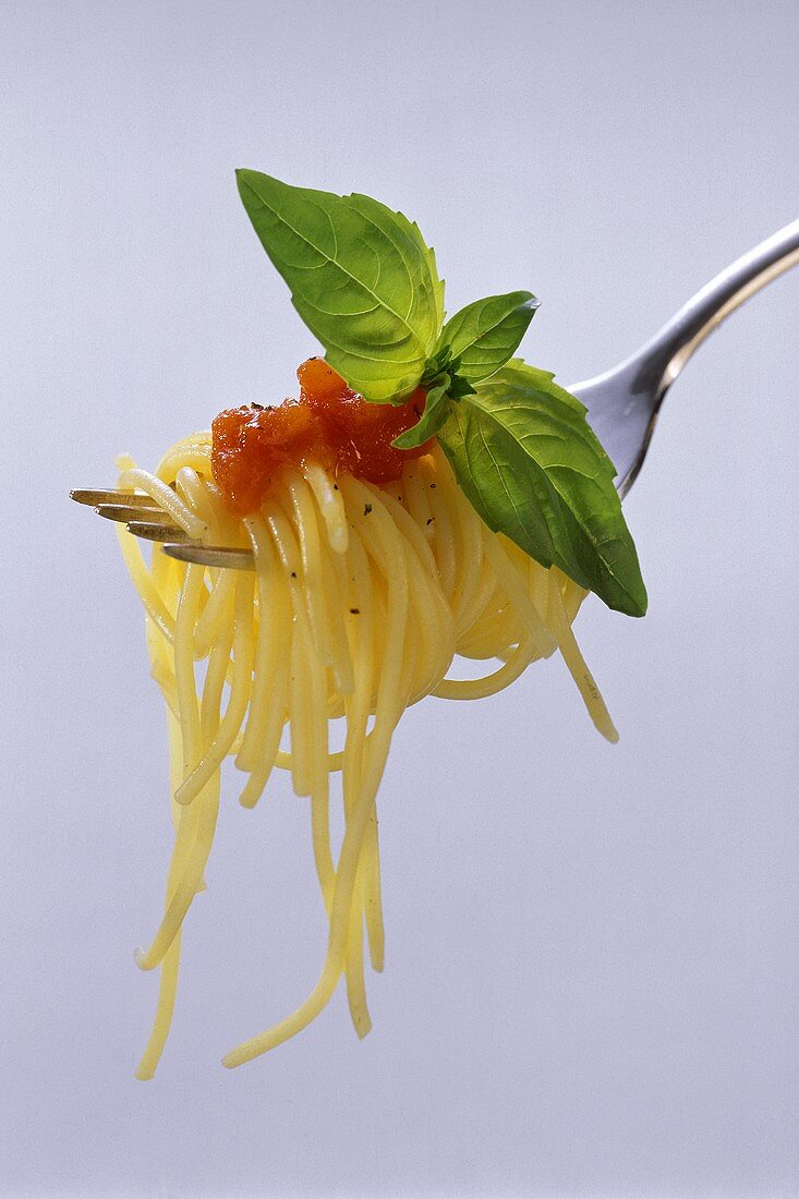 Spaghetti mit Tomatensauce & Basilikumblättchen auf Gabel