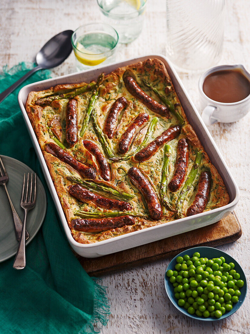 Toad in the hole (fried sausages baked in egg batter, England) with green vegetables