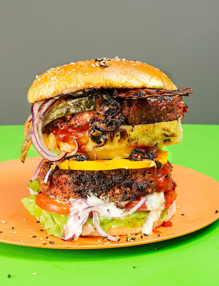 Veganer Big-Burger mit 'V-Speck' (veganem Speckersatz), Röstzwiebeln und Paprika