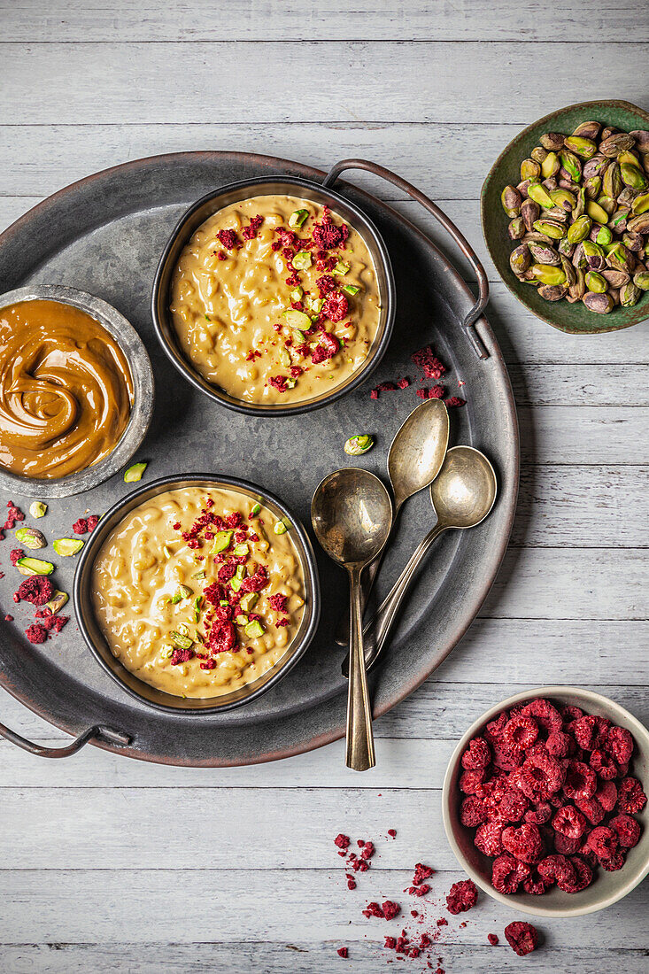 Rice pudding with dulce de leche sauce, raspberries, and pistachios