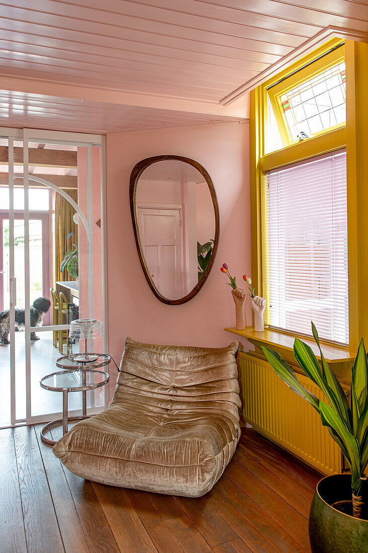 Leather armchair in eclectic living room with pink walls and yellow window frames