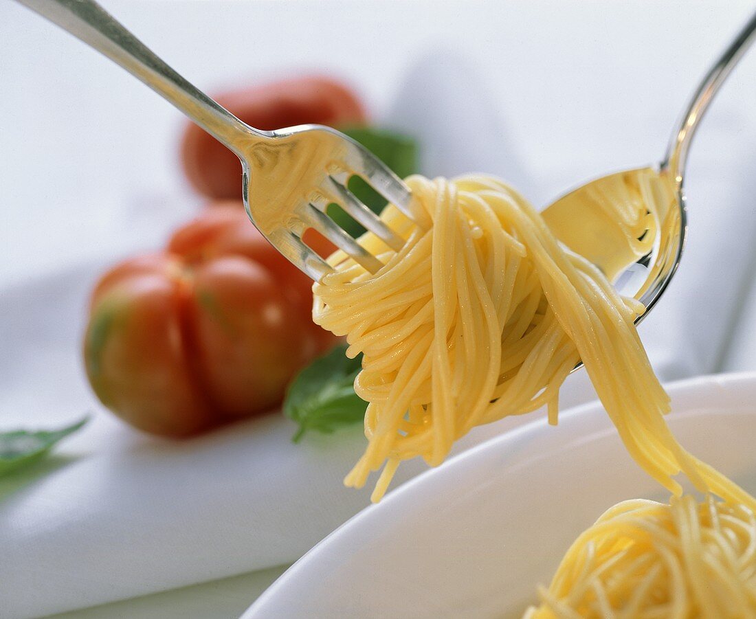 Spaghetti überm Teller mit Löffel auf Gabel drehen
