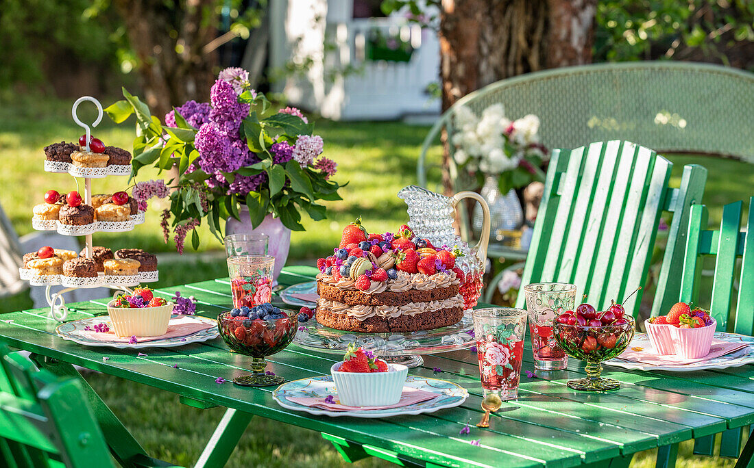 Laid garden table with cake and fresh berries in summer