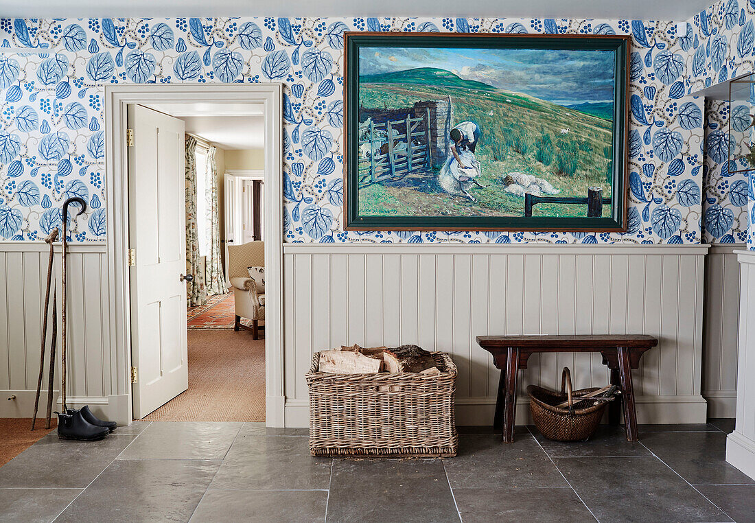 Log basket and large artwork in tiled hallway of North Yorkshire farmhouse, UK