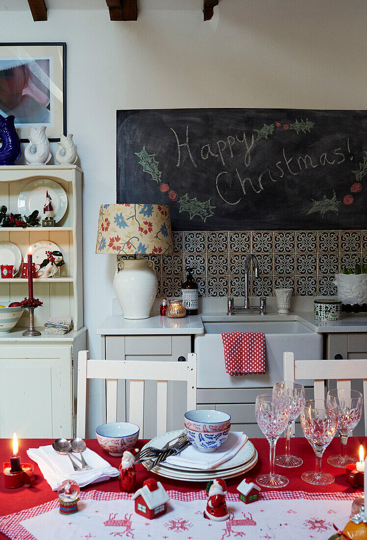 Happy Christmas' auf einer Tafel über dem Waschbecken mit Gläsern und Geschirr auf dem Tisch