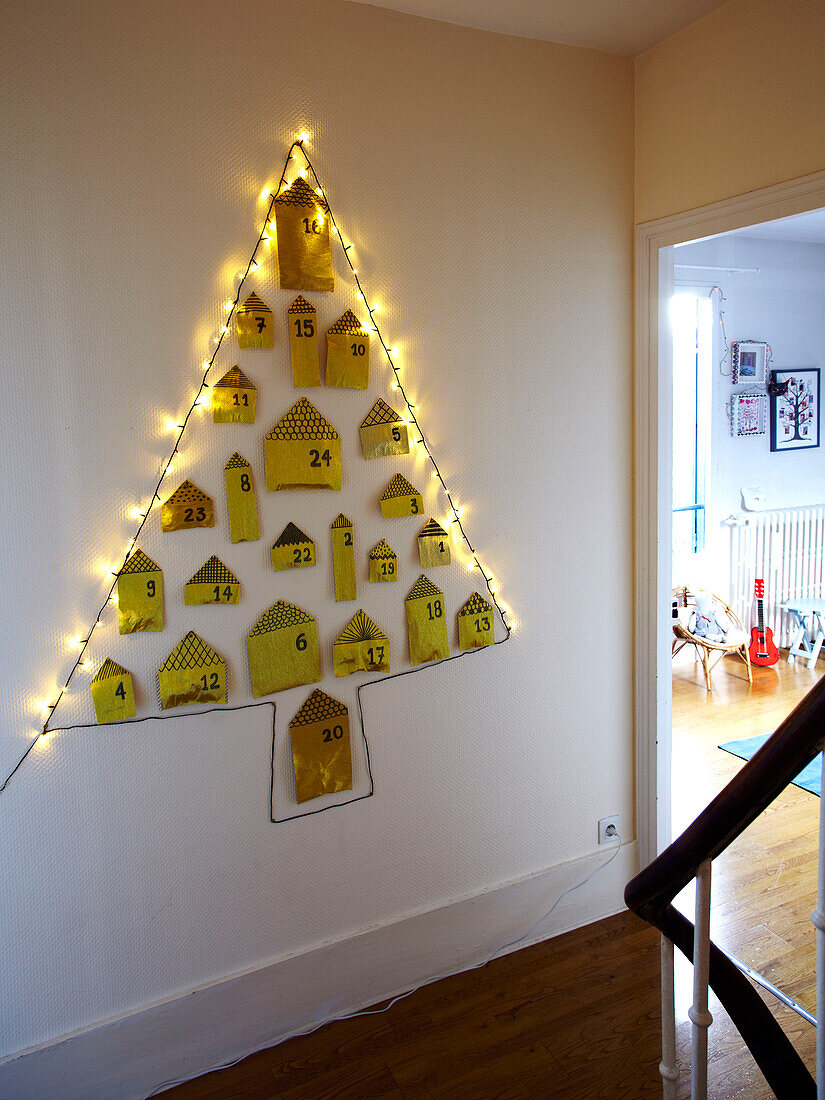 Full-size advent calendar in the shape of a Christmas tree on hallway wall of French family home