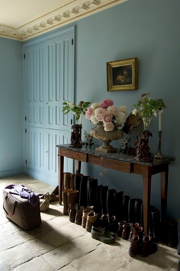 Row of shoes under table in entrance hall of old house