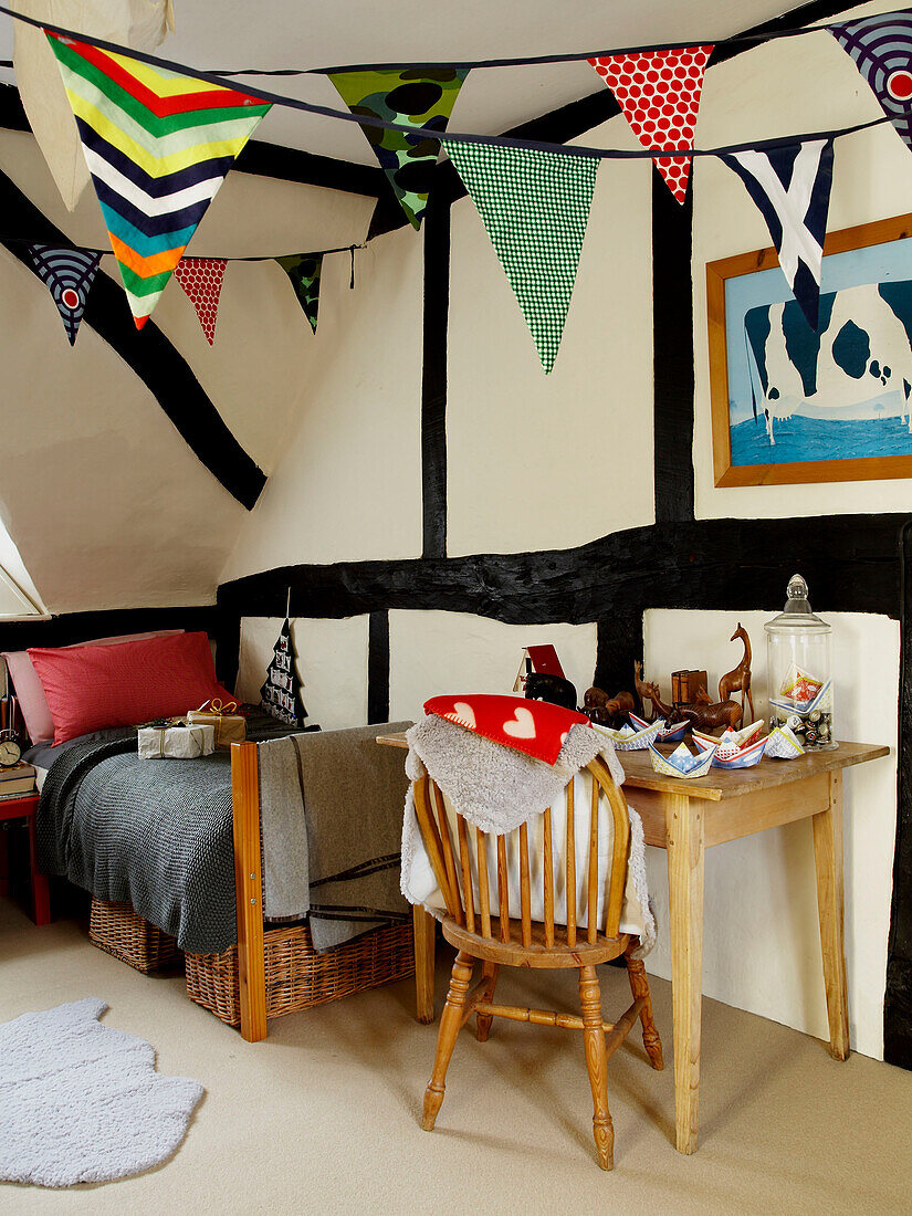 Einzelbett mit Schreibtisch und Stuhl im Kinderzimmer mit Fähnchen in einem Cottage in Herefordshire, England, UK