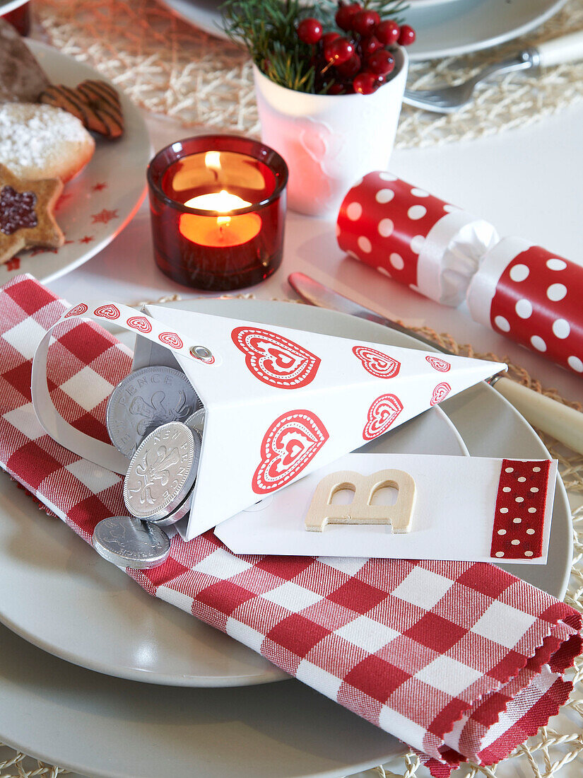 Silver coins on gingham napkin at place setting with Christmas cracker in Polish family home