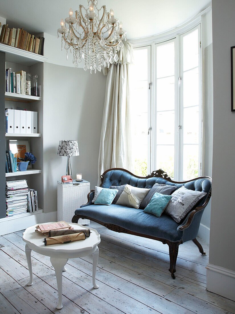 Blue sofa with painted coffee table under vintage chandelier in Winchester home, Hampshire, UK