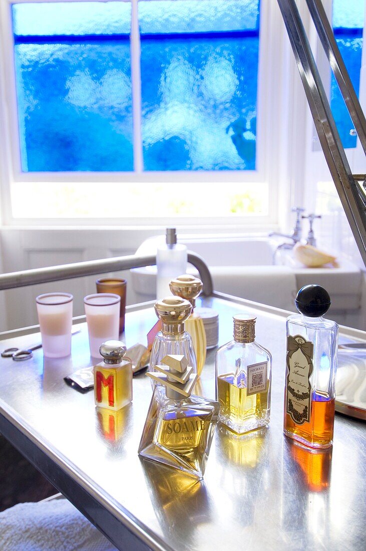 Bottles with perfumes and oils on metal shelf in bathroom