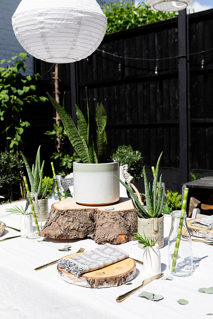 Holzscheite als Platzdeckchen mit Bronzebesteck auf einem Tisch mit Papierschirm in Colchester garden Essex UK