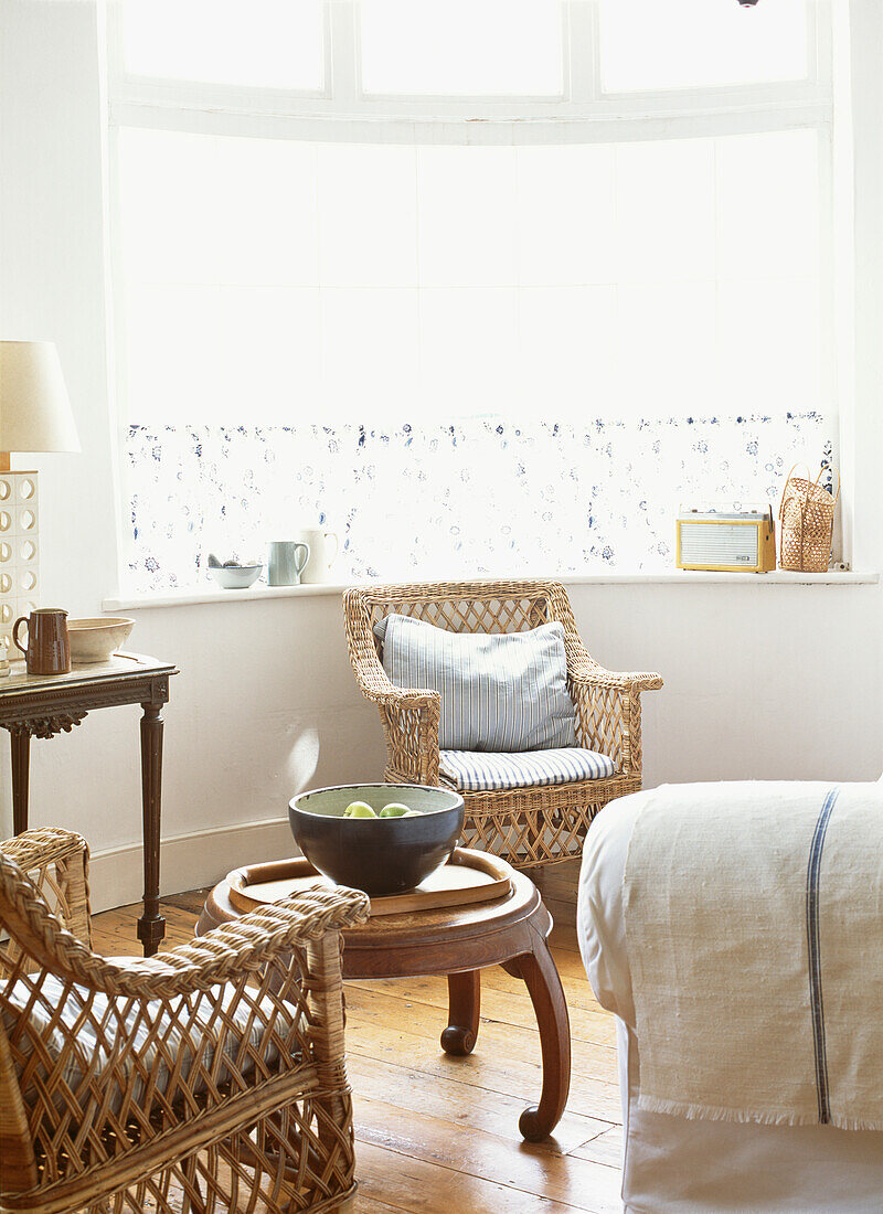 Living room with bay window and wicker armchairs next to Chinese coffee table