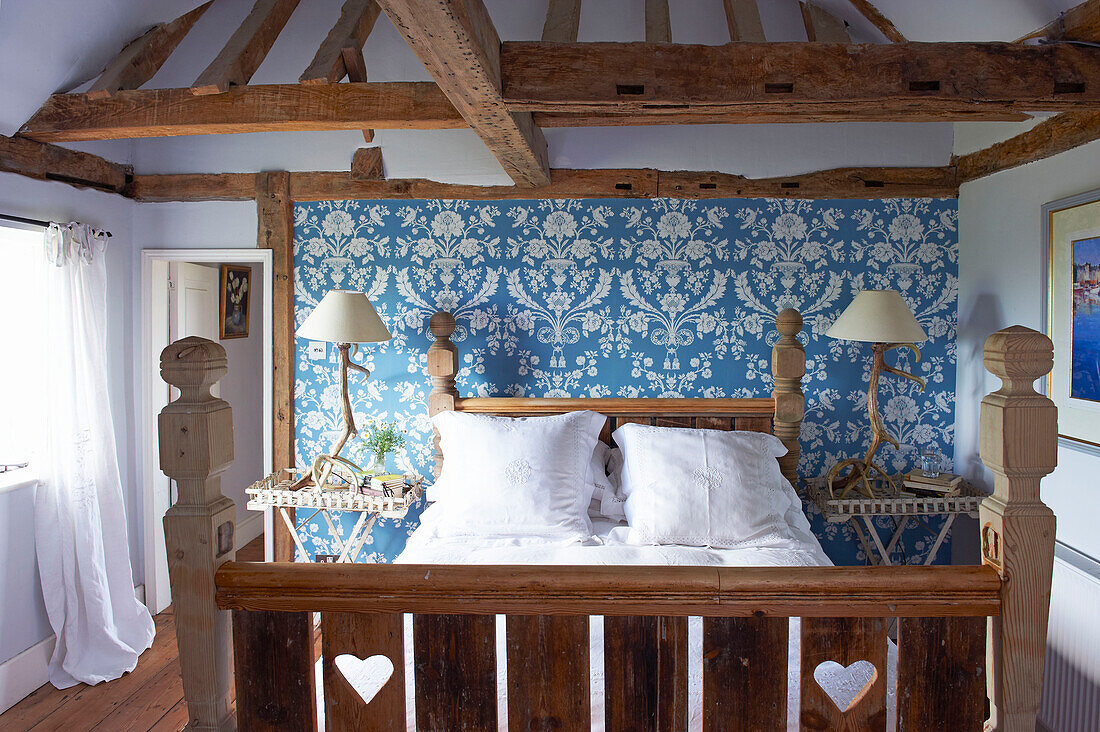 Hearts carved into wooden footboard of bed in blue room of timber framed Iden farmhouse, Rye, East Sussex, UK