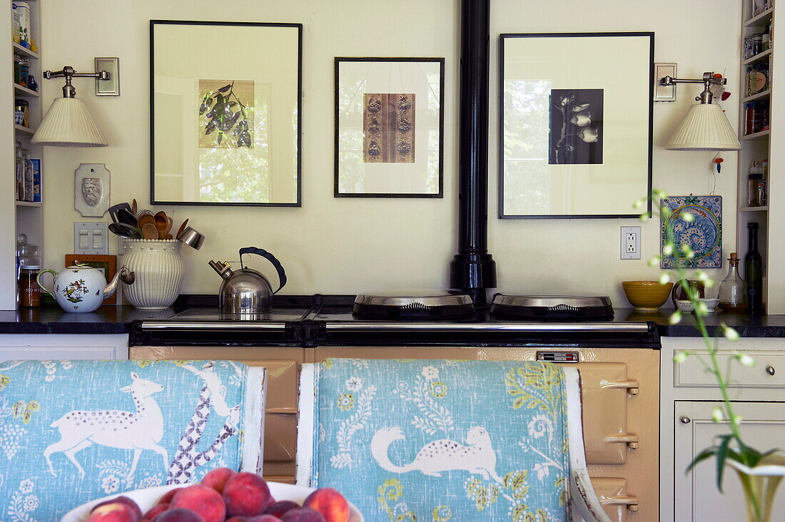 Range oven and artwork with upholstered chairs in kitchen of Massachusetts home, New England, USA