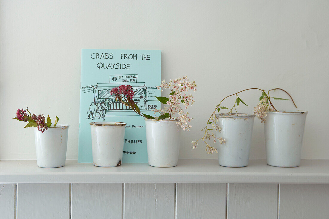 Display of wild flowers in enamel pots on a shelf