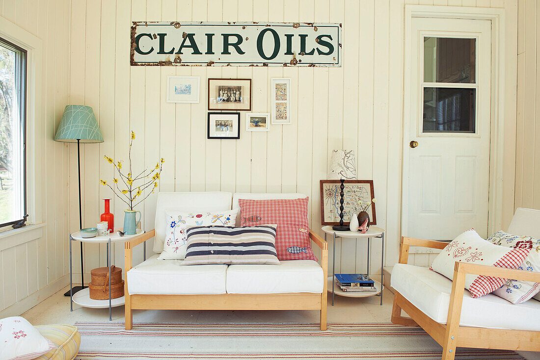 Two seater sofa with patterned cushions and vintage metal sign in Berkshires home, Massachusetts, Connecticut, USA