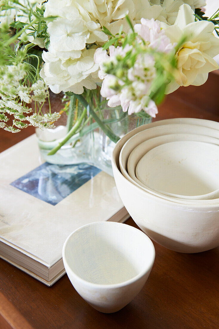 Cut flowers and bowls with book on tabletop in Austerlitz home, Columbia County, New York, United States