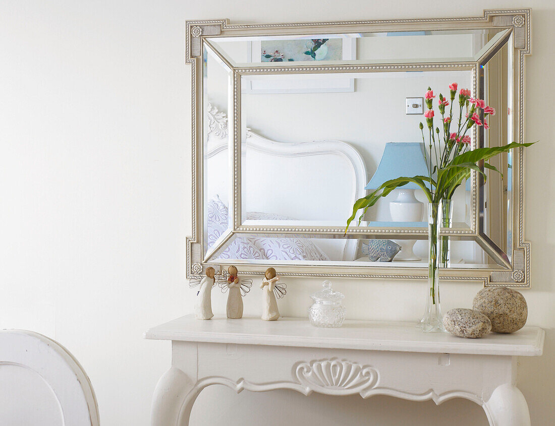 Decorations on shelf in bedroom reflected in mirror