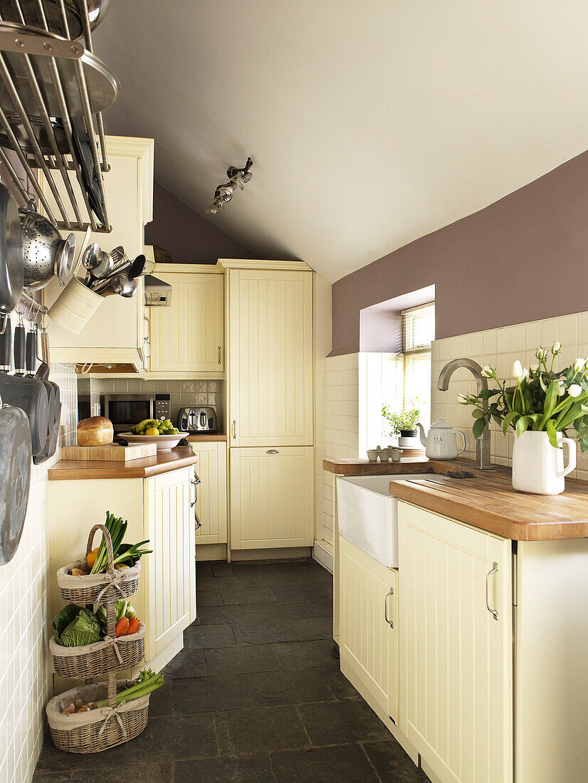 Pan rack and vegetable basket in galley kitchen of Welsh cottage, UK