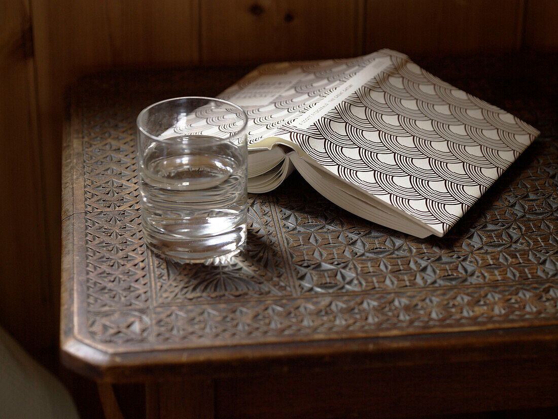 Upside down book and drink water on carved table in Shropshire chapel conversion England, UK