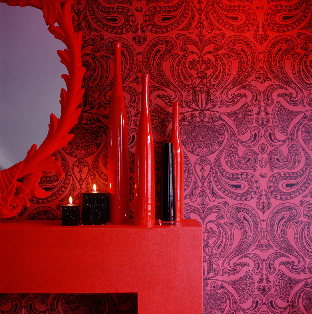 Detail eines in Rot und Schwarz gehaltenen Wohnzimmers mit Kaminsims und Haushaltswaren