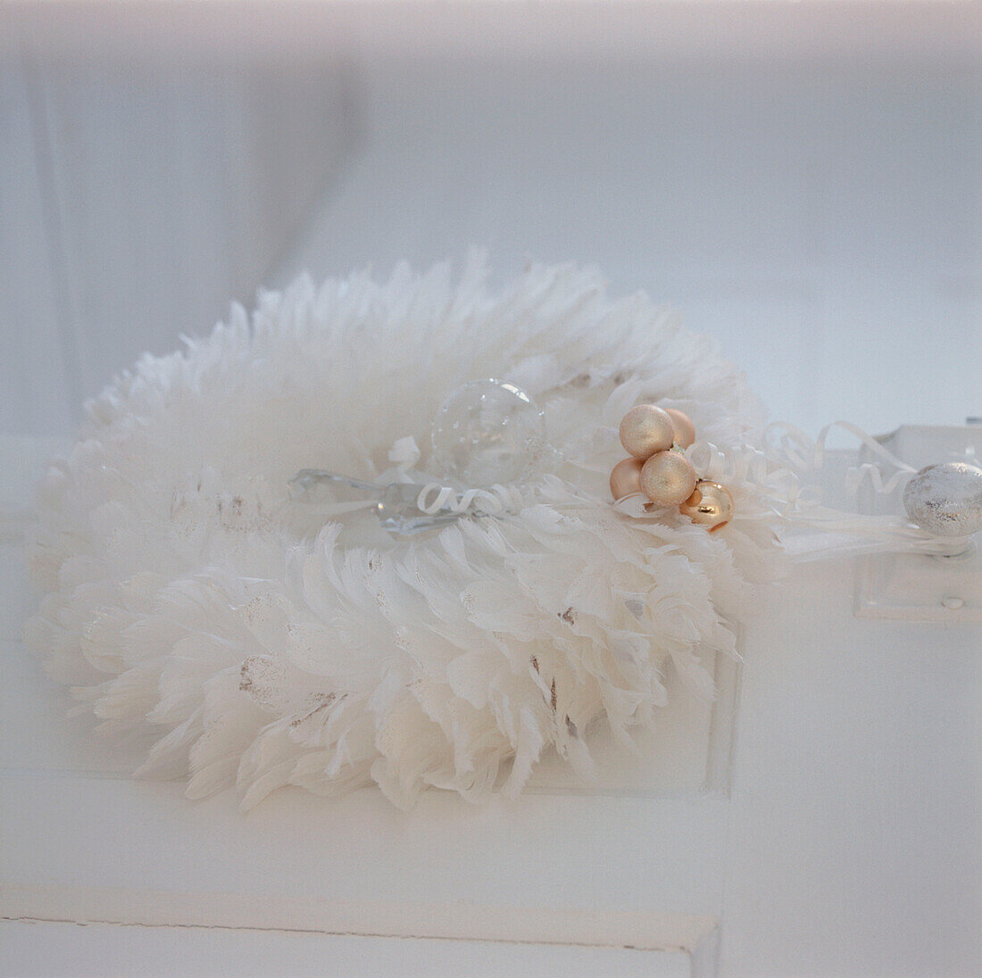 White feathered wreath Christmas decoration hung on a white door