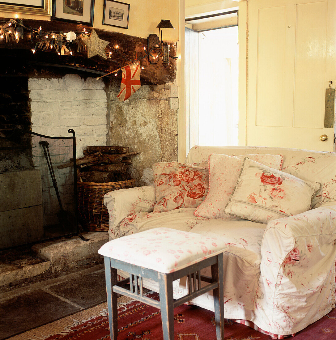 Wohnzimmer im Landhausstil mit Sofa aus geblümten Stoffen, Fußhocker und Kaminofen