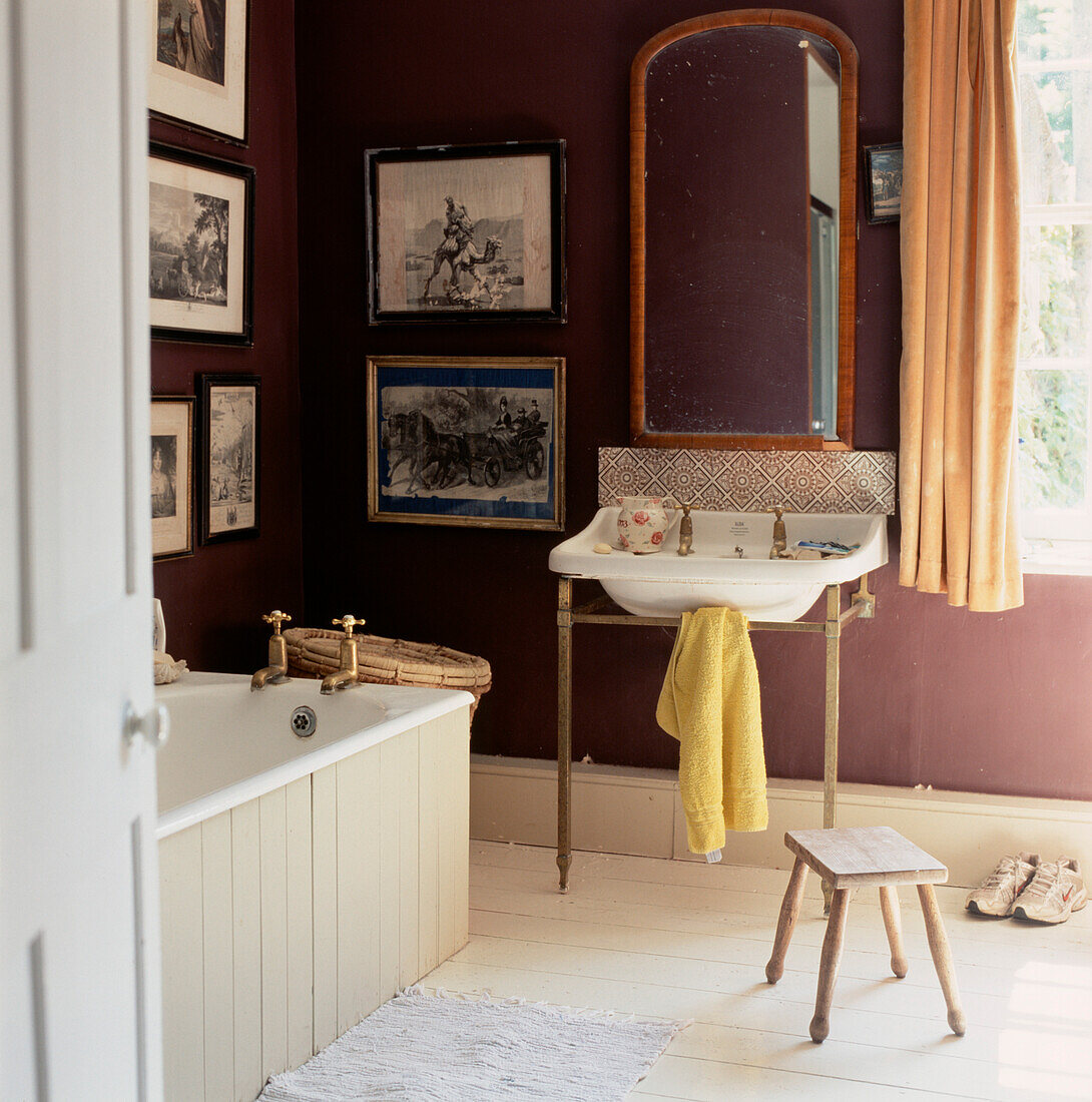 Stilvolles Badezimmer mit altem Waschbecken, Badewanne und dunkelviolett gestrichenen Wänden